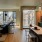 2 Bedroom Apartments in Downtown Seattle, WA - West Edge - Modern Kitchen with Stainless Steel Appliances, Wood-Patterned Cabinetry, White Tile Backsplash, White Countertops, Large Island with Seating and Hanging Lights, with a Large Window Nearby