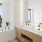 Downtown Seattle, WA Luxury Apartments - Large Bathroom With Glazed Porcelain Tile, Built-In Lighting, Textured Cabinetry, A Large Vanity Mirror, Dual Sinks, Hard-Surface Flooring, A Window, And A Tub With City Views.