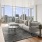 Downtown Seattle, WA Luxury Apartments - Open Floor Living Room with Hard Surface Flooring, High Ceilings, A Fireplace, And Floor To Ceiling Windows With City Views.